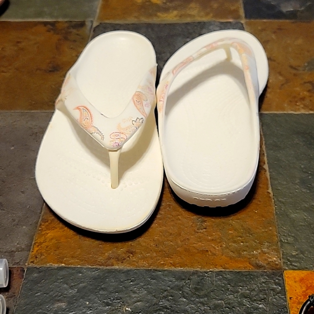 Crocs size 4 wide flip flops with paisley print.